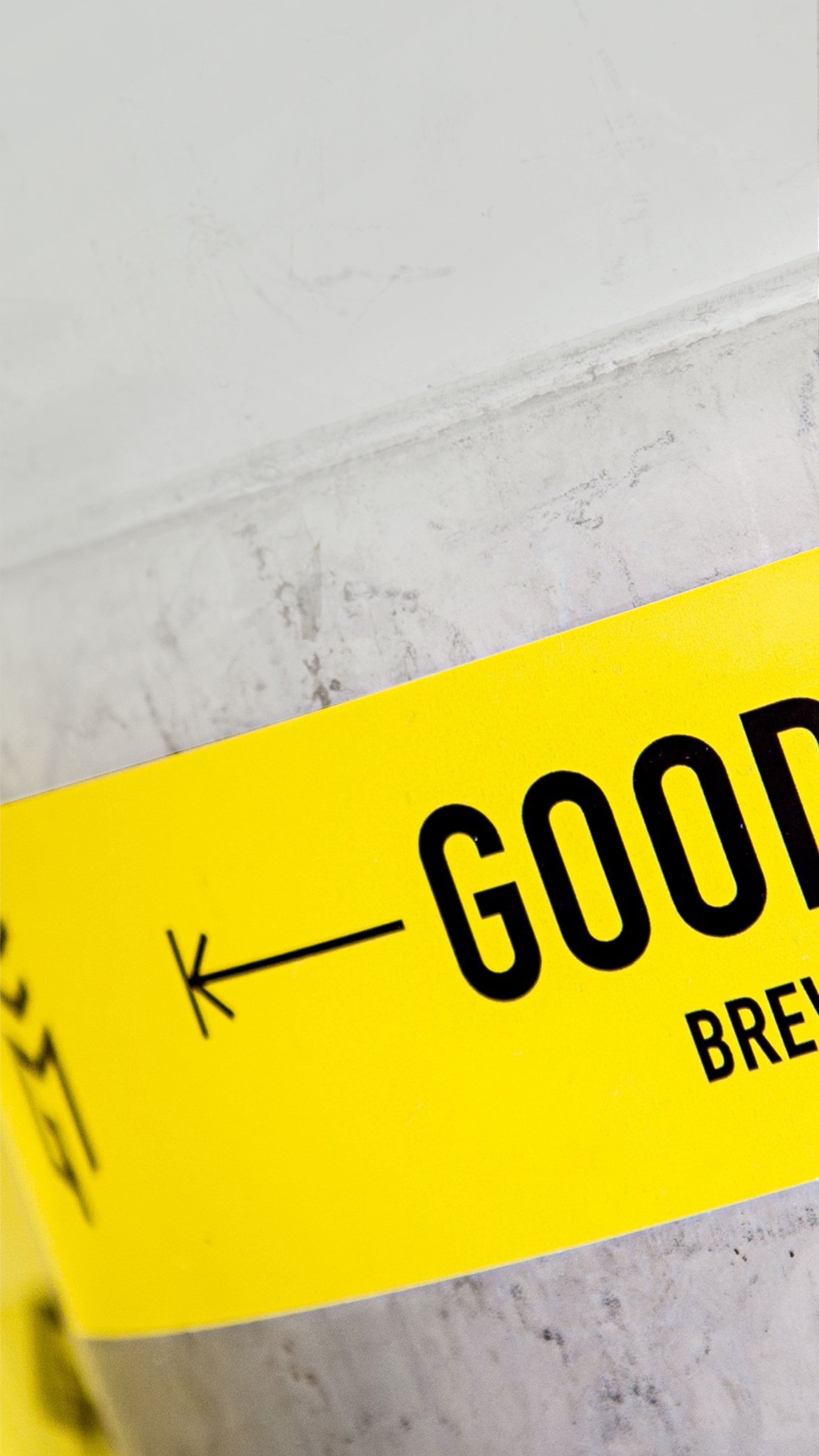 Yellow custom brand vinyl sticker with 'Good Measure Brewing Co.' branding logo on a concrete surface.