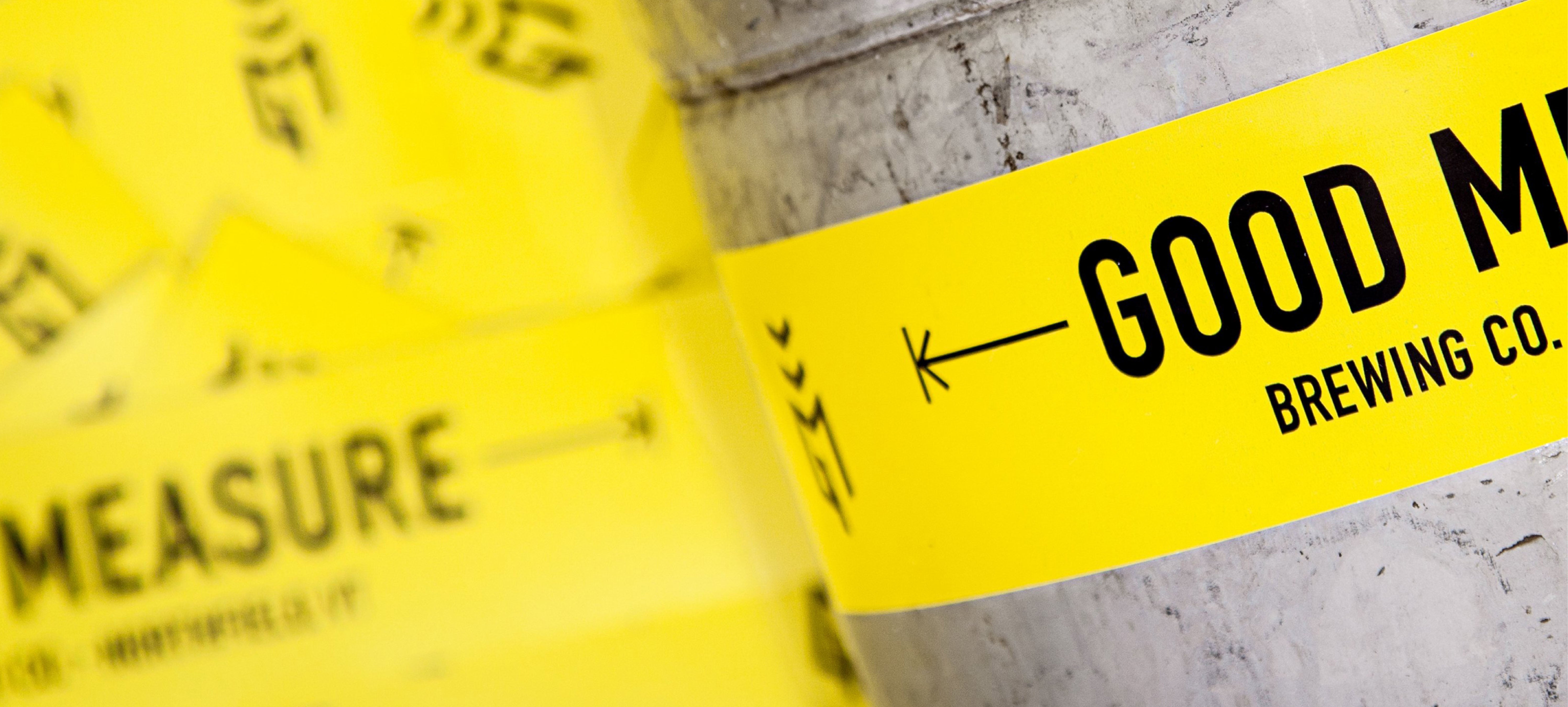 Yellow custom brand vinyl sticker with 'Good Measure Brewing Co.' branding logo on a concrete surface.