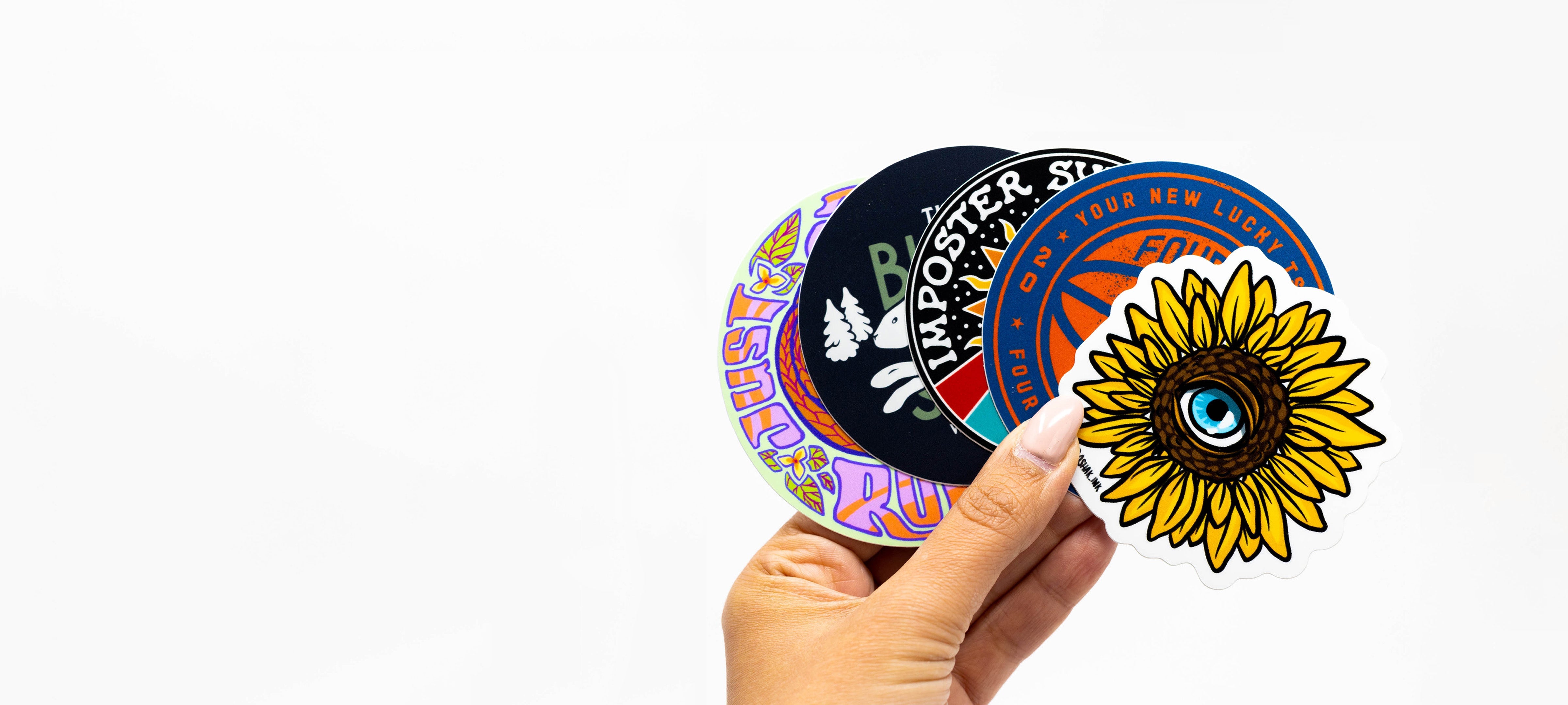 Hand holding custom vinyl die cut stickers with illustrations and graphic images of sunflower basketball brand logo and rabbit